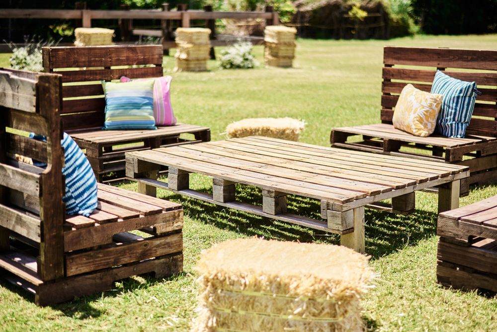 Rustic outdoor seating area with wooden pallet furniture arranged on grass.