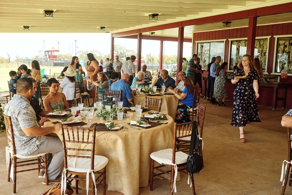Large covered outdoor venue with guests seated at round tables for a celebration.