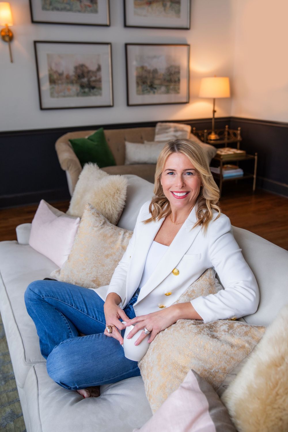 Casual business portrait on couch with decorative pillows and framed artwork.