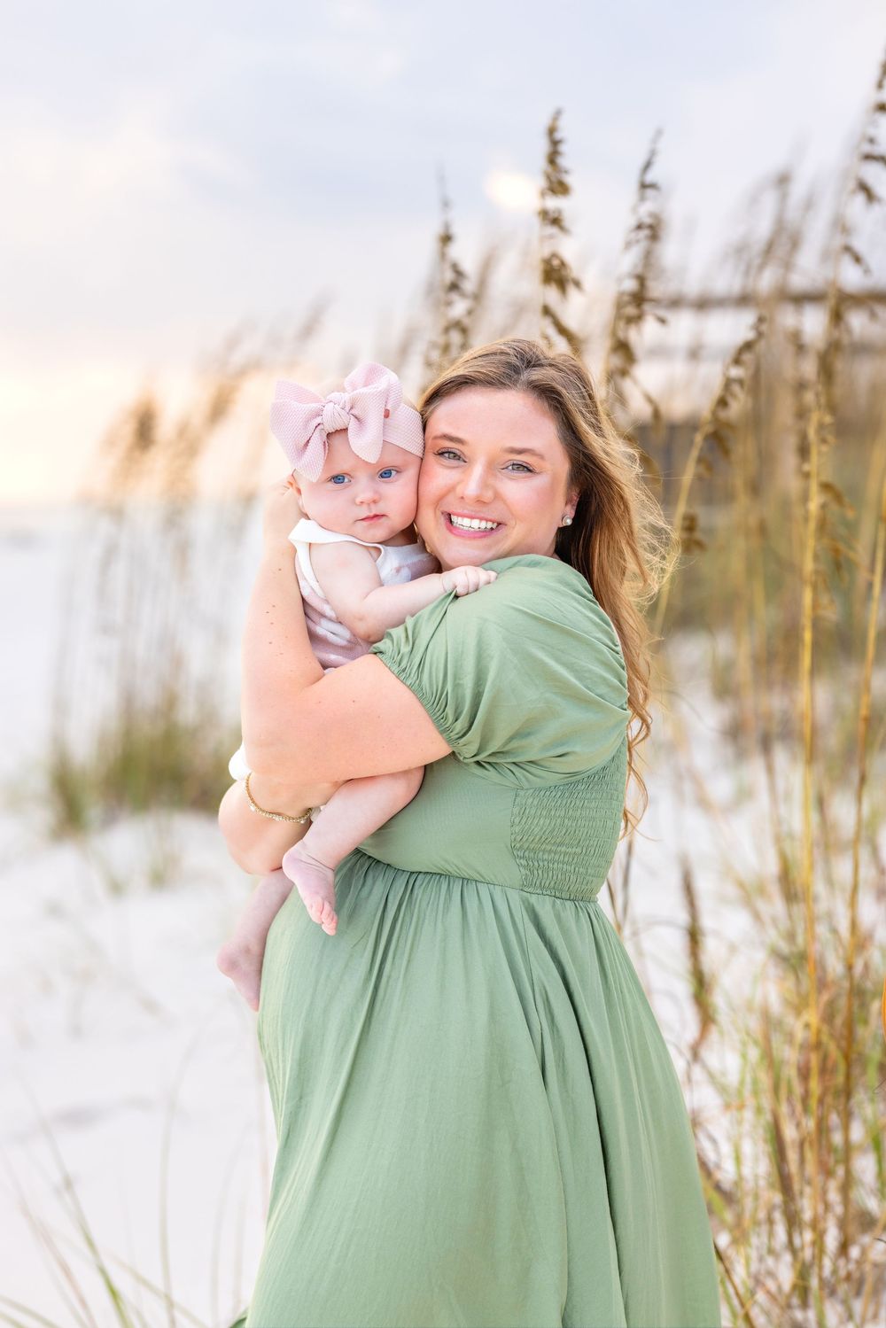 A seaside portrait in soft lighting shows a mint green dress against beach grass and sand dunes.