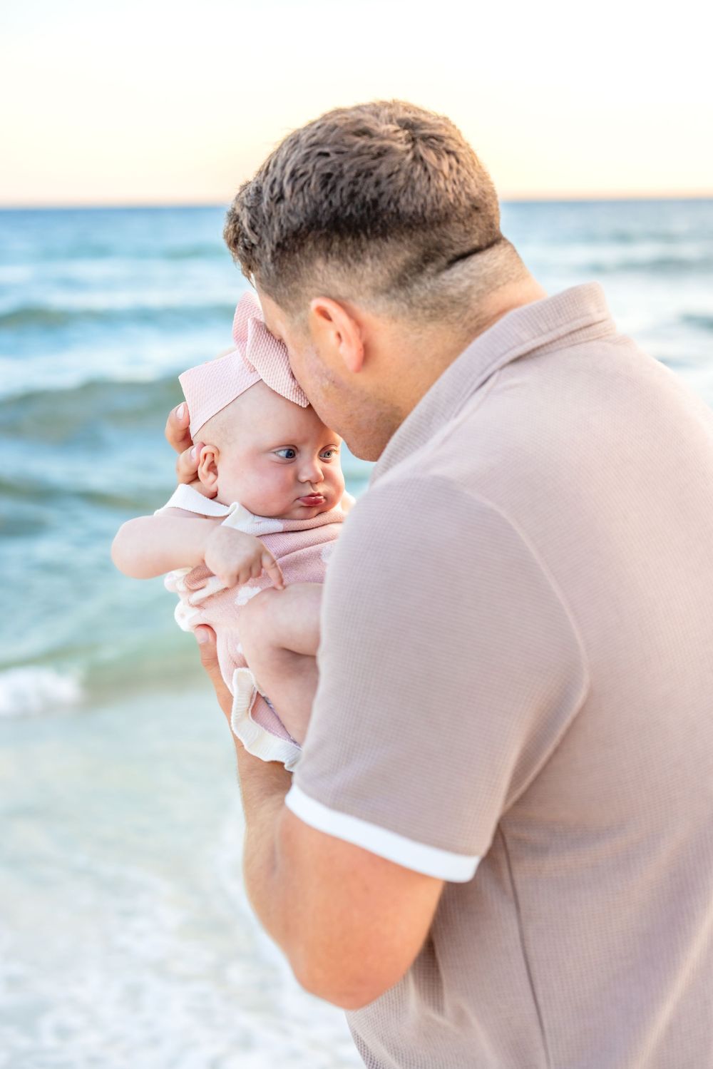 A tender moment between parent and child is captured in a series of photos at the beach during sunset.