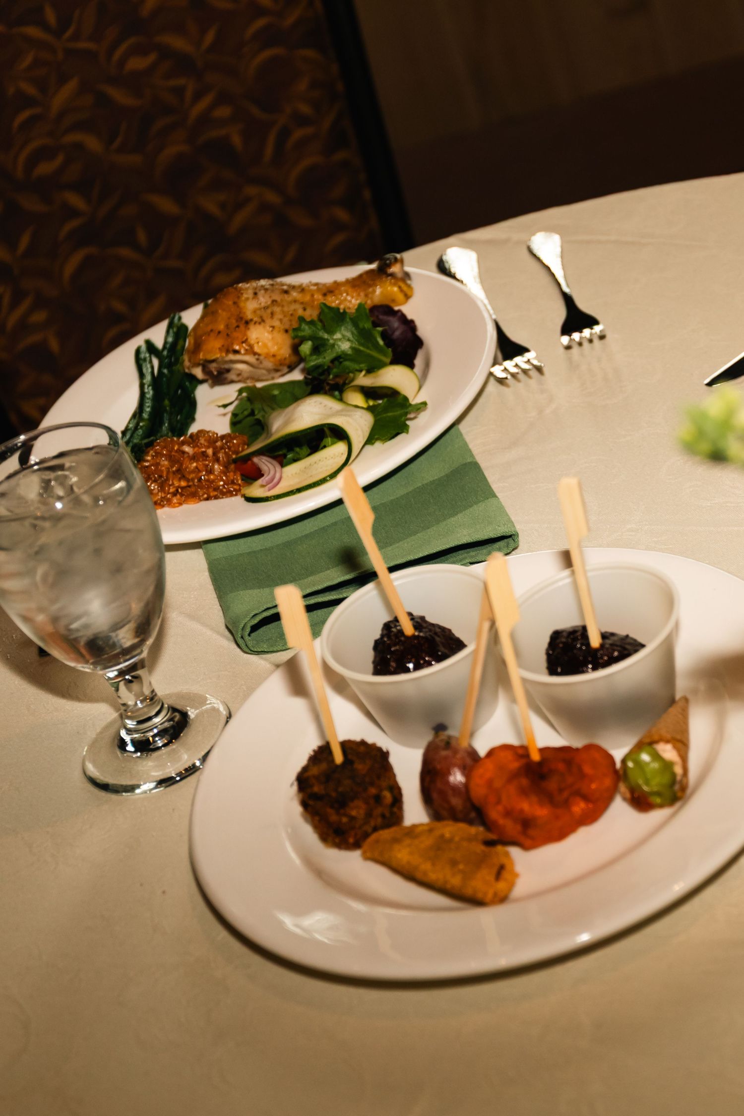 A series of elegantly plated appetizers served on white plates with bamboo skewers and dipping sauces at an upscale restaurant.