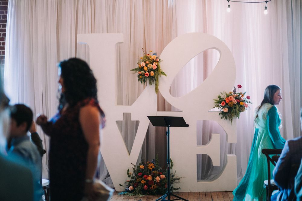 Wedding party members in turquoise dresses stand in line during an elegant indoor ceremony.