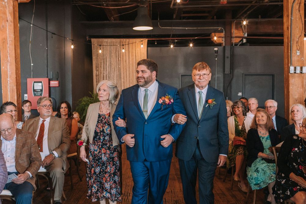 Wedding guests react with joy and excitement during an emotional moment at an industrial-style venue reception.