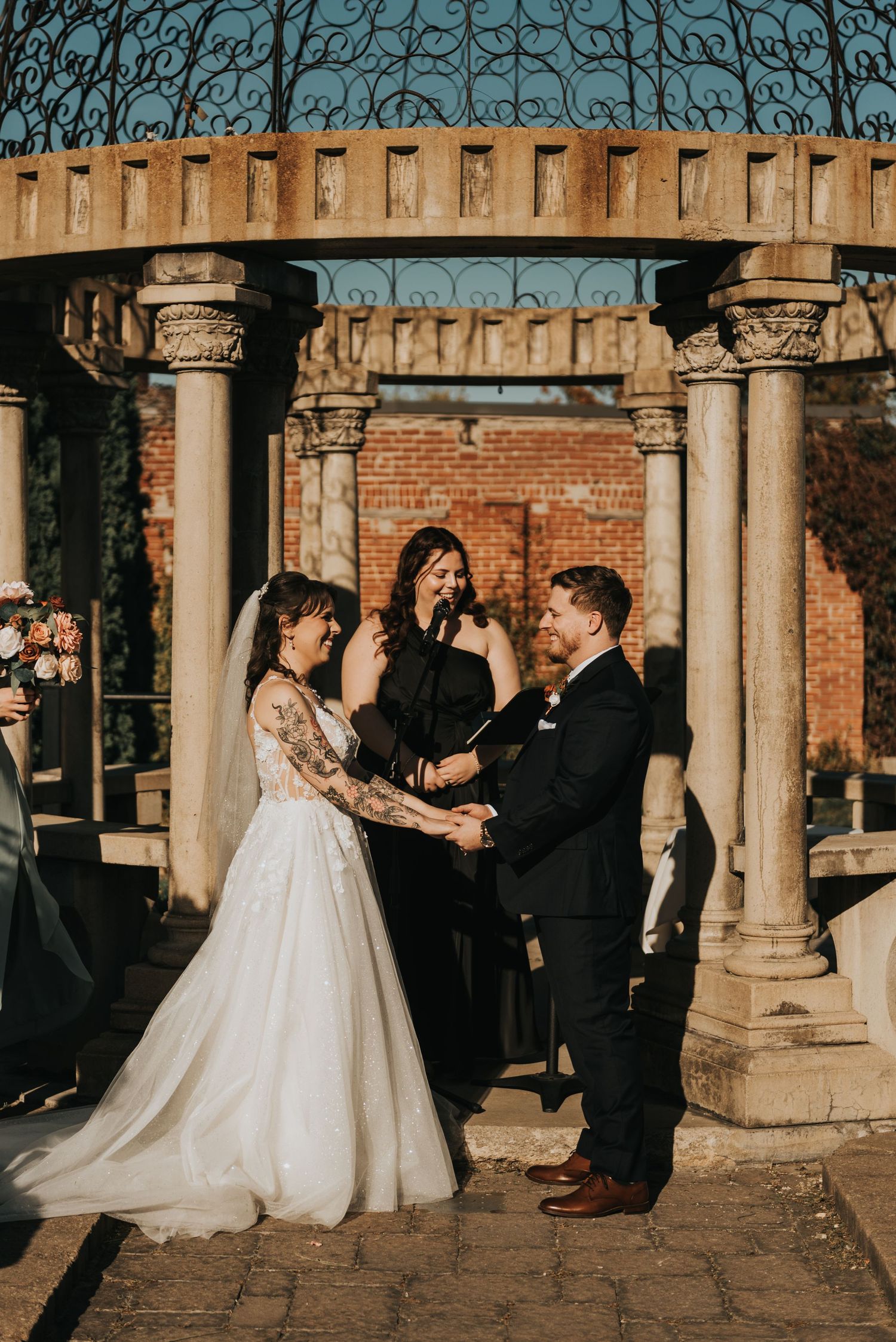 A romantic wedding couple shares intimate moments under a stone colonnade at sunset.