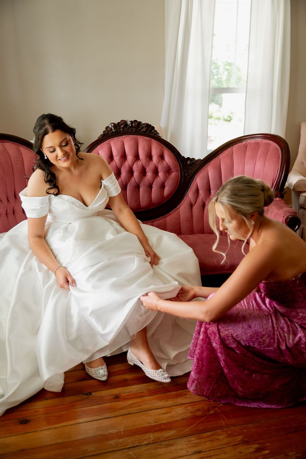 Elegant bridal portraits on pink vintage sofa showing off white wedding gown details.