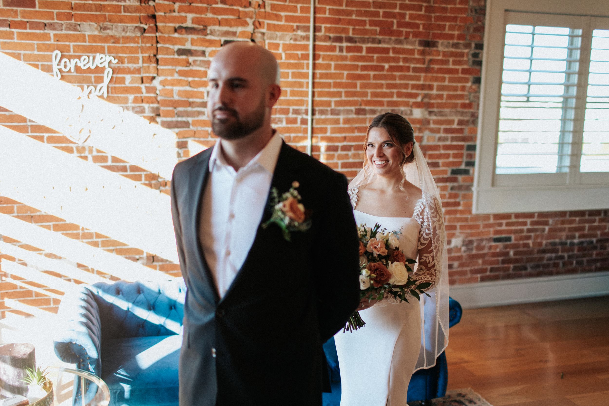 Wedding couple sharing intimate moment during first look in industrial brick venue.