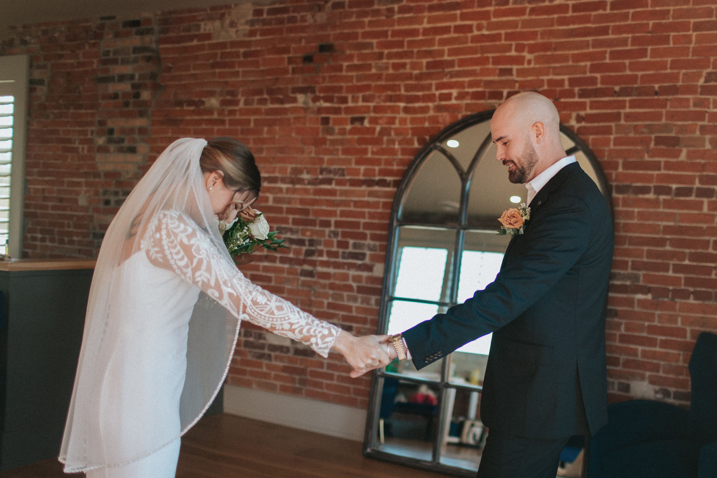 Tender moment between couple during wedding first look in industrial brick space.
