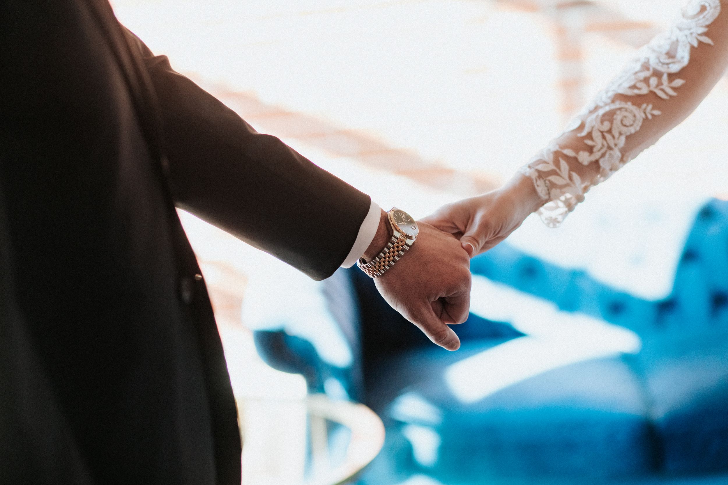 Close-up of hands touching during wedding first look moment with natural lighting.