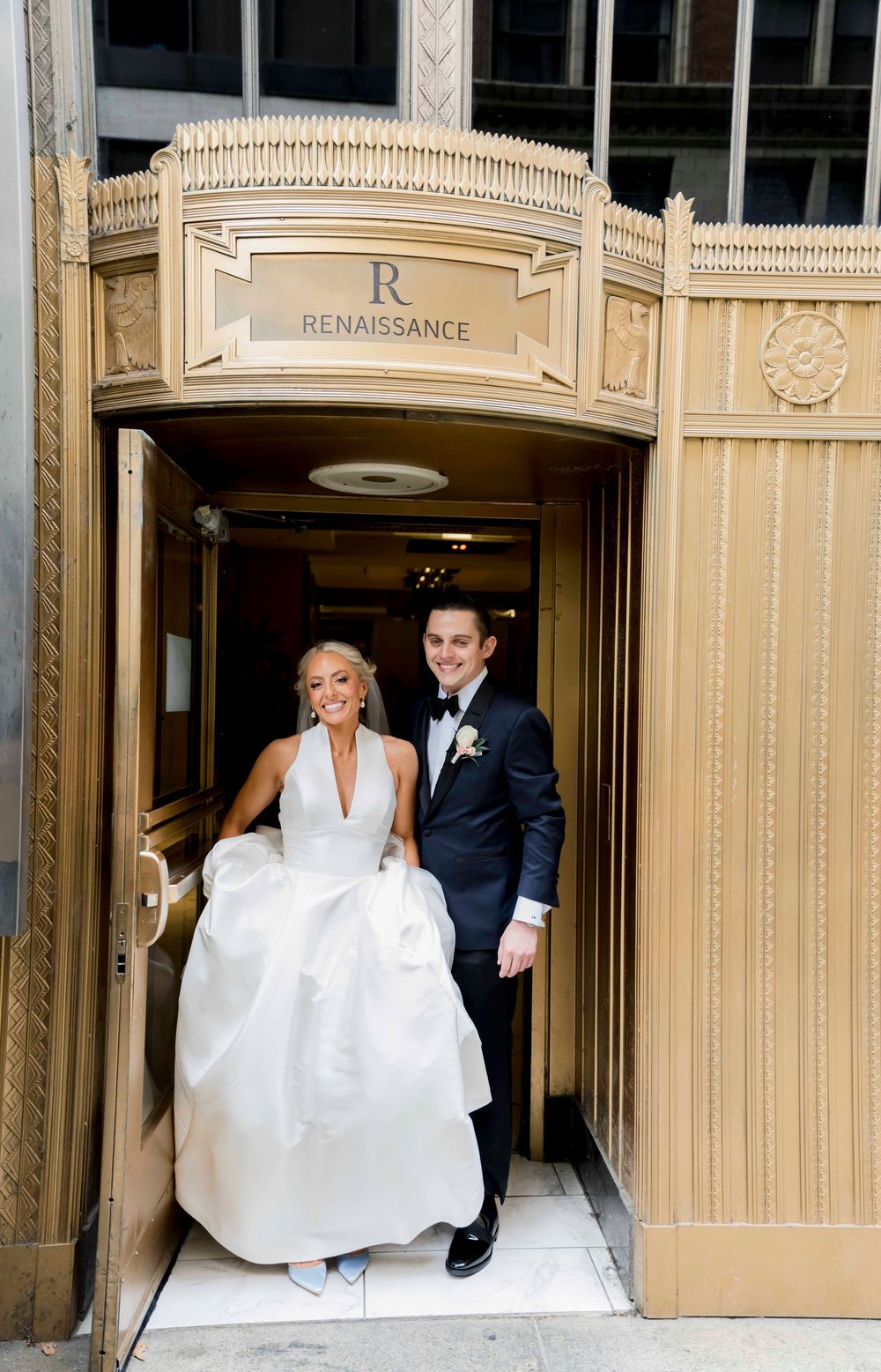 A couple exits through an ornate Renaissance doorway on their wedding day at a historic venue.