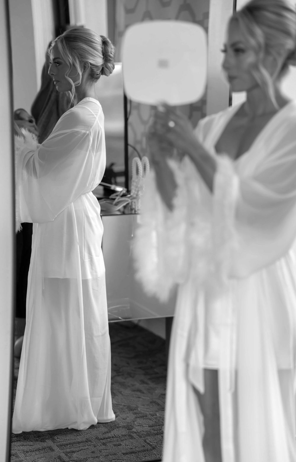 A series of blurred black and white photographs showing people in white dresses moving in a dance-like sequence.