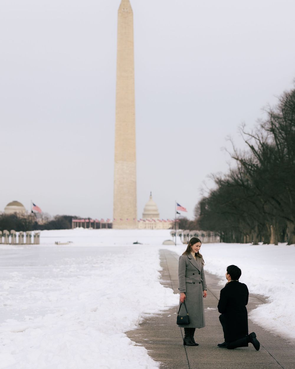 People walking and sitting near the Washington Monument on a snowy winter day in Washington DC.