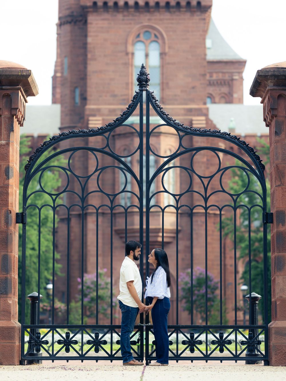 A couple stands in silhouette against an ornate wrought iron gate  At the Enid Haupt Garden in Washington DC