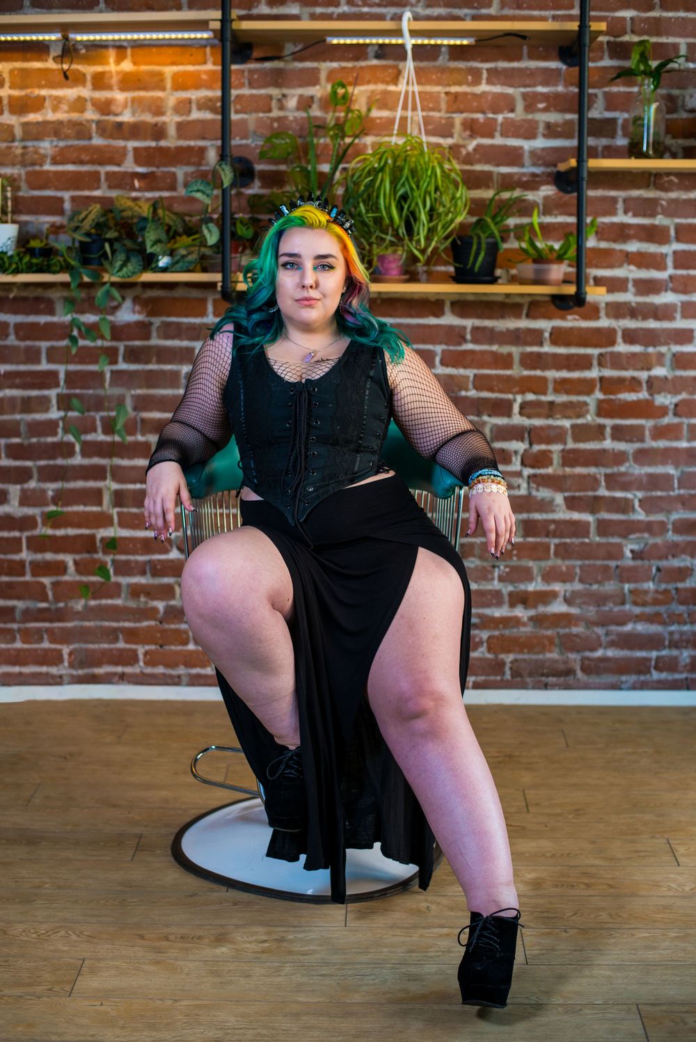 Alternative style photoshoot with black outfit against brick wall backdrop.