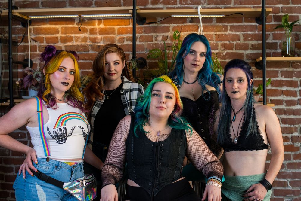 Group photo session with diverse styling against industrial brick backdrop.