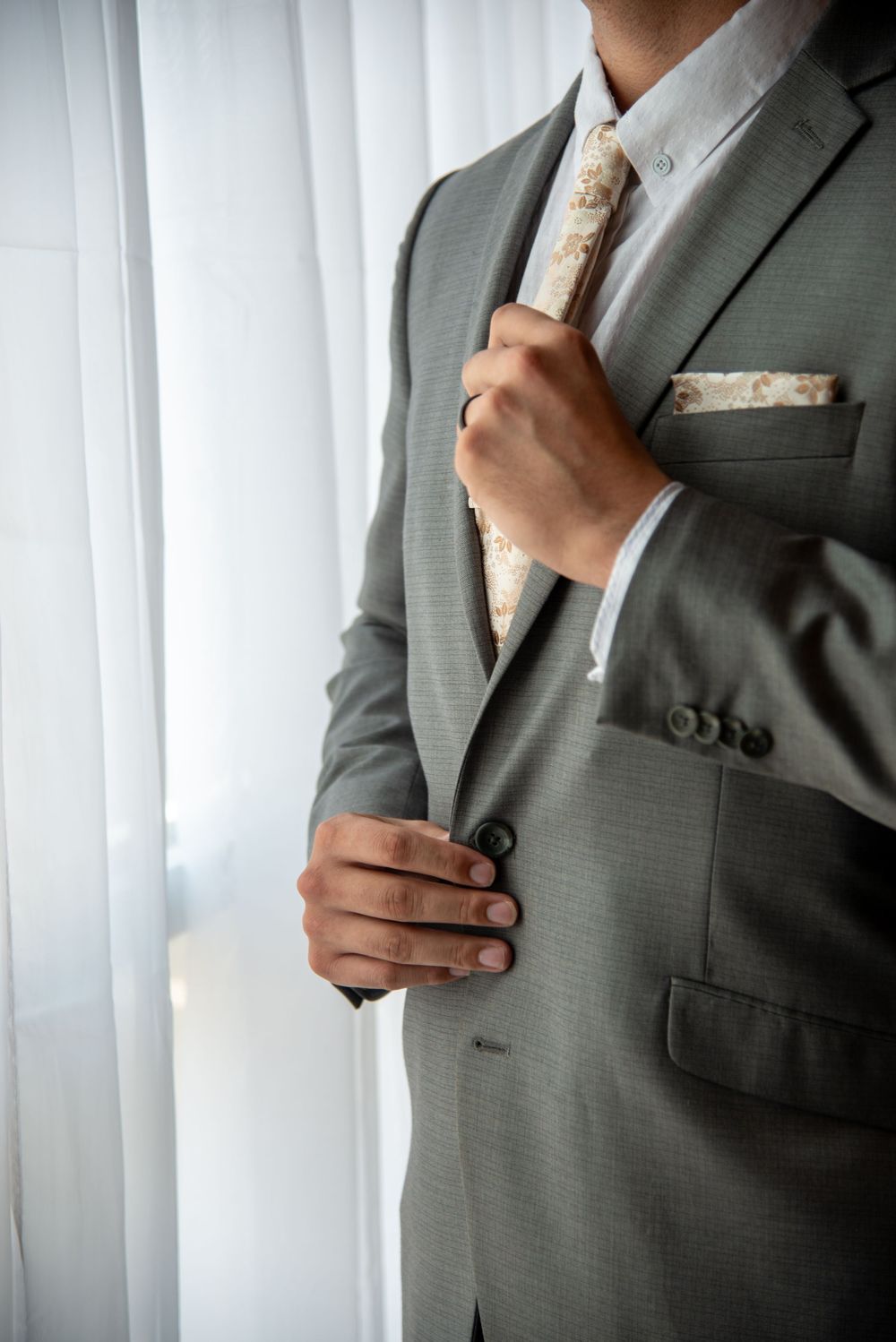 Close-up shots of a grey suit jacket and floral tie being adjusted.