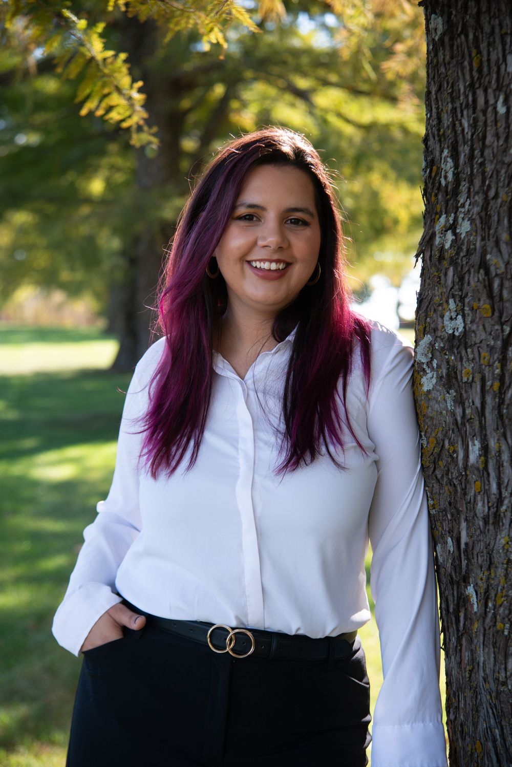 Portrait session in a park setting showing white blouse and dark skirt outfit with autumn trees.