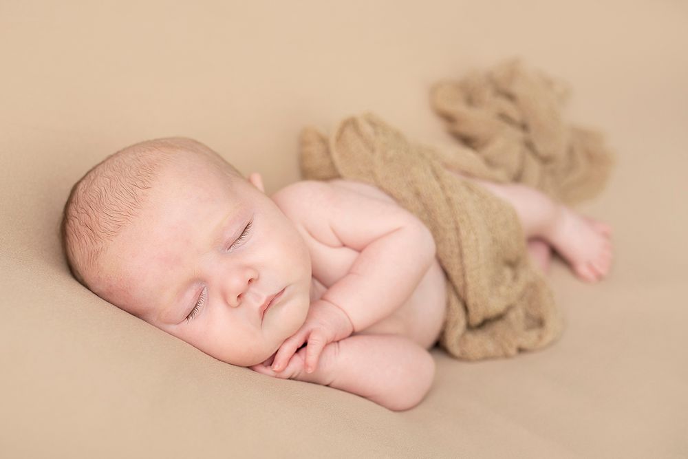 Newborn baby photographed in a studio on a neutral blanket