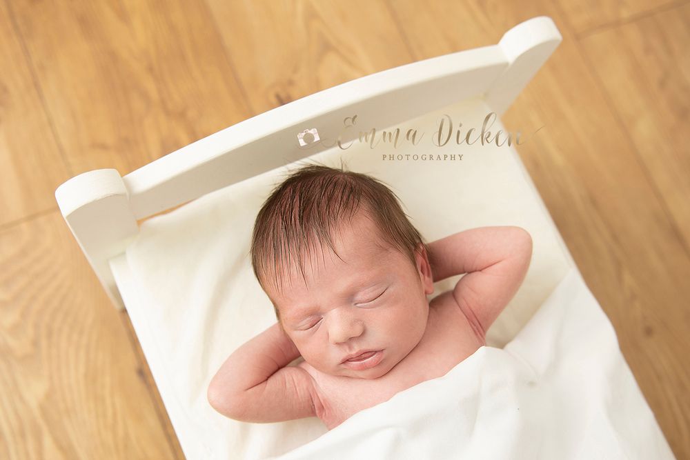 Newborn baby photographed sleeping with his hands behind his head
