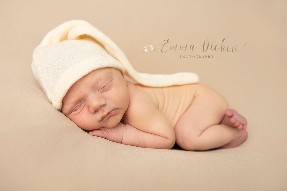 Newborn baby boy wearing a sleepy hat photographed on a neutral blanket