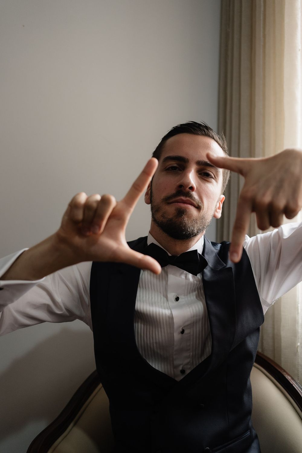 Series of four dramatic black and white portraits showing someone adjusting their formal attire in moody lighting.