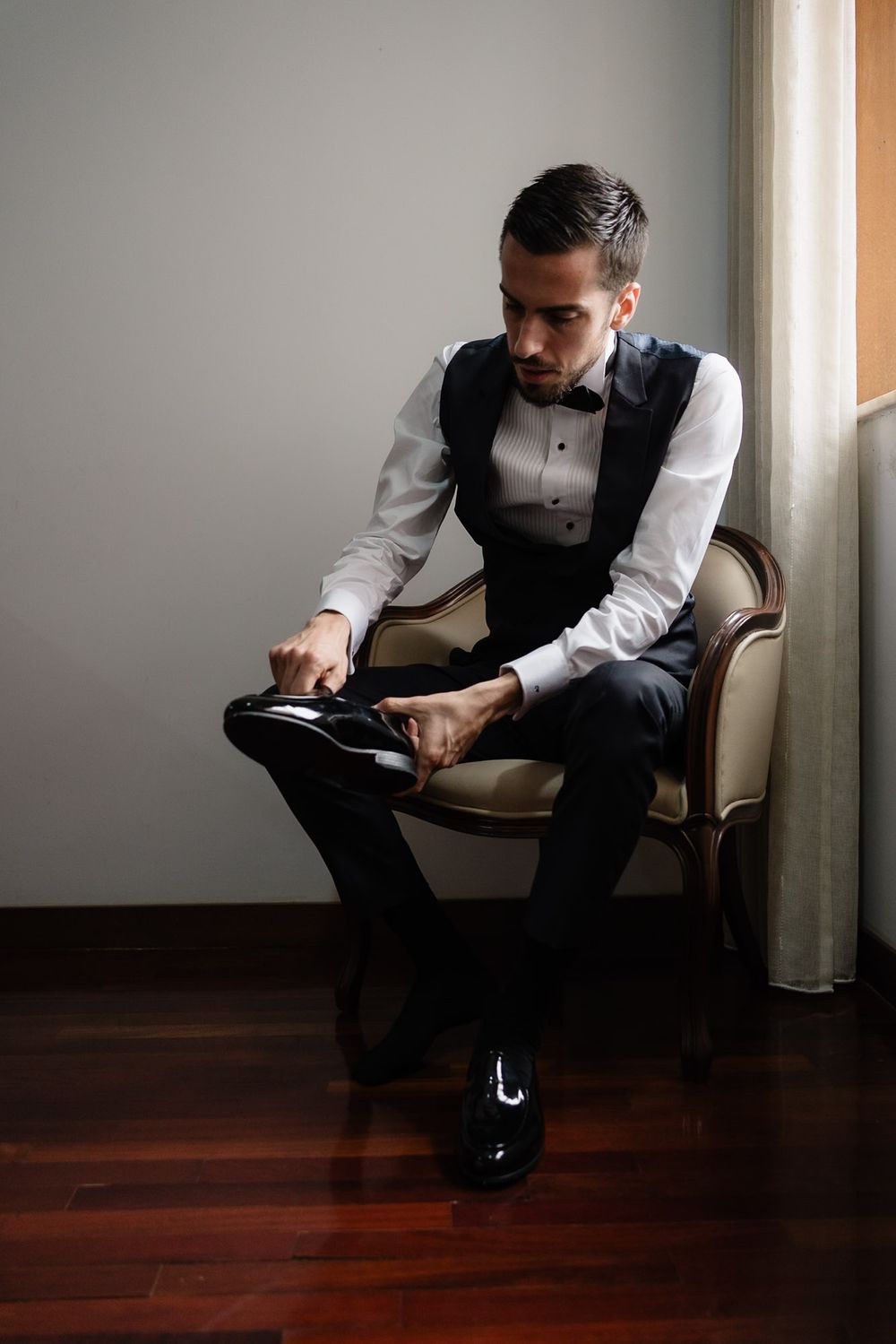 Moody portrait series of someone in business attire sitting thoughtfully in a chair by a window.