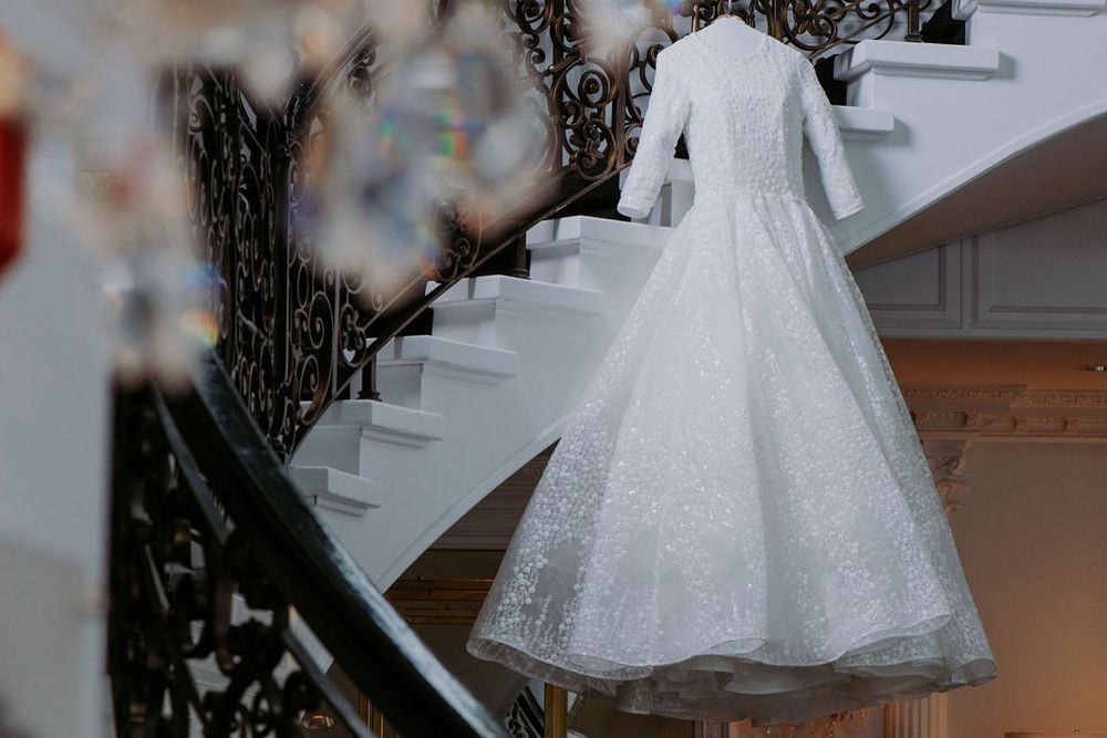 A flowing white wedding dress with sparkly tulle fabric hangs elegantly in a bridal boutique setting.