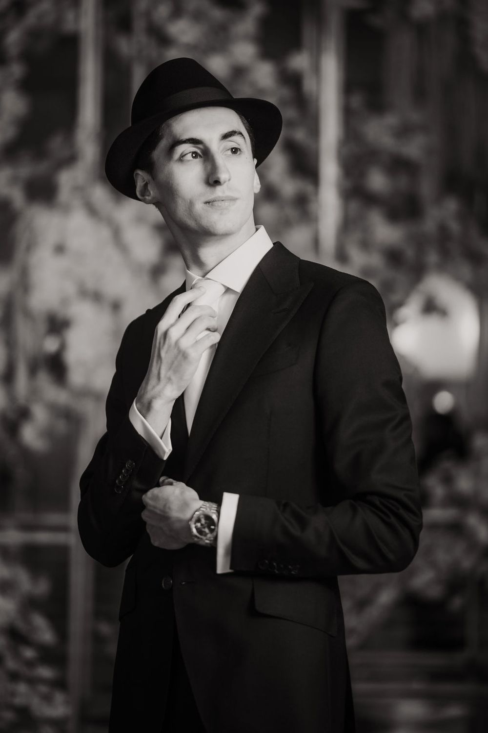 Classic black and white portrait of a gentleman in formal attire with a fedora hat and suit.