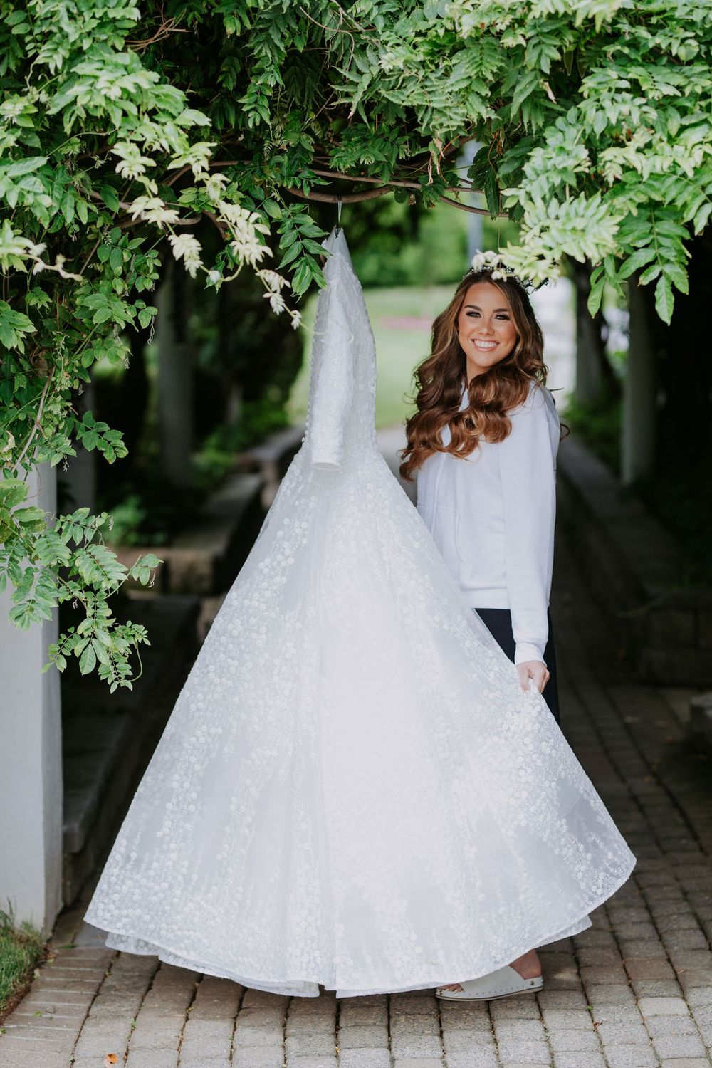 Elegant white wedding dress displayed outdoors under green foliage with multiple artistic angles.