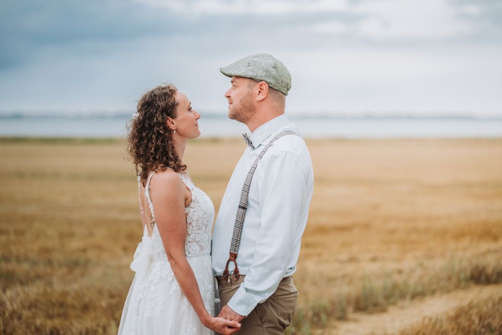 A couple shares a romantic moment together in a golden wheat field at sunset.
