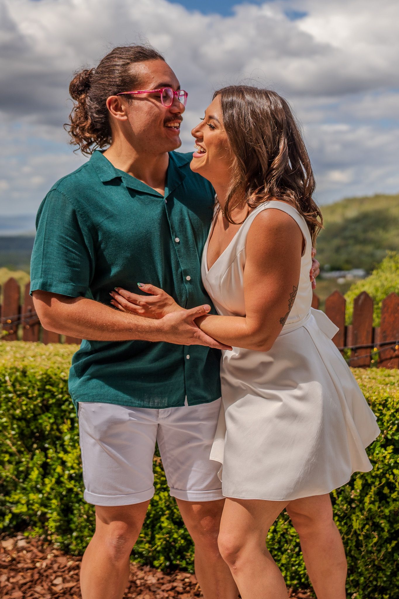 A couple sharing a laugh together in front of a scenic outdoor landscape.