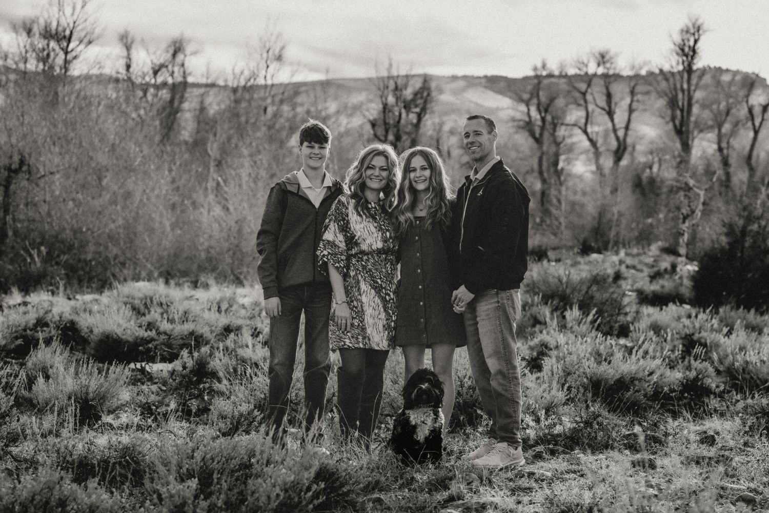 A group of people pose together in a black and white landscape photograph.