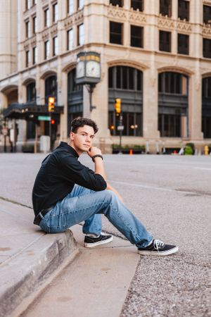 Urban portrait session with person sitting on yellow street lines near historic architecture.
