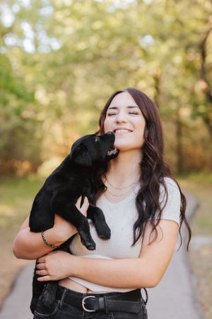 Joyful moments captured between person and black dog in outdoor autumn setting.