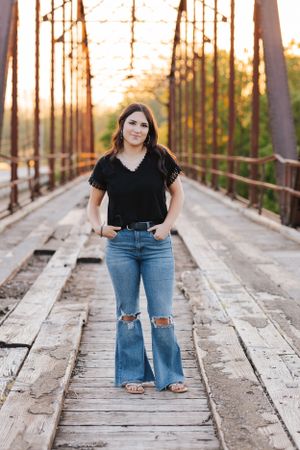 Rustic wooden bridge photo session at sunset with distressed jeans and casual style.
