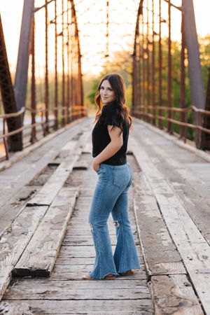 Fashion photography on vintage wooden bridge with dramatic sunset lighting.