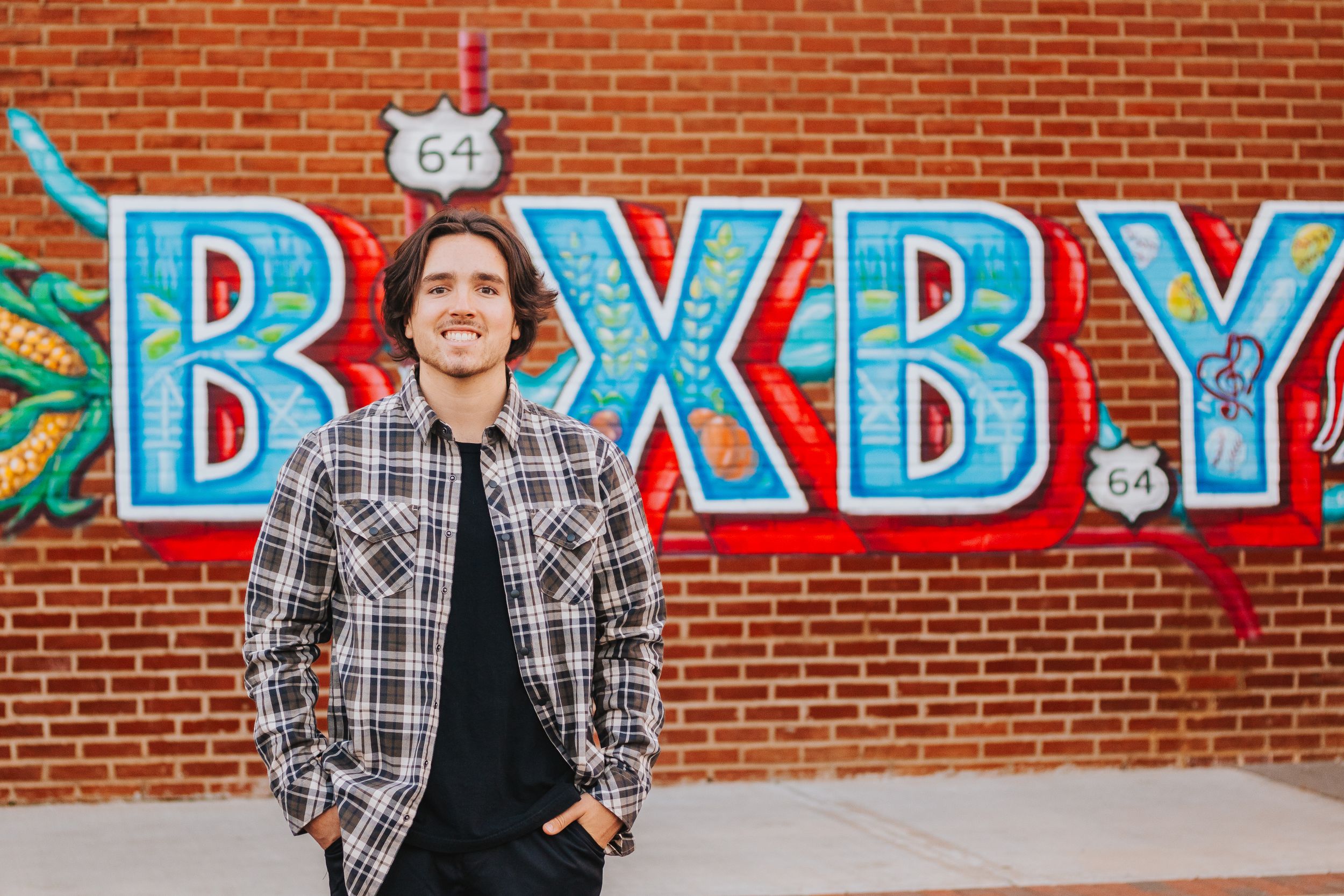 Urban portrait session against colorful Route 66 themed mural and brick wall.