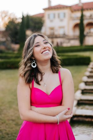 A joyful portrait session featuring a bright pink dress against an elegant garden backdrop.