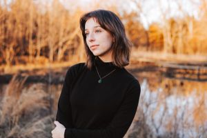 Autumn outdoor photoshoot featuring dark clothing against golden foliage and water reflections.
