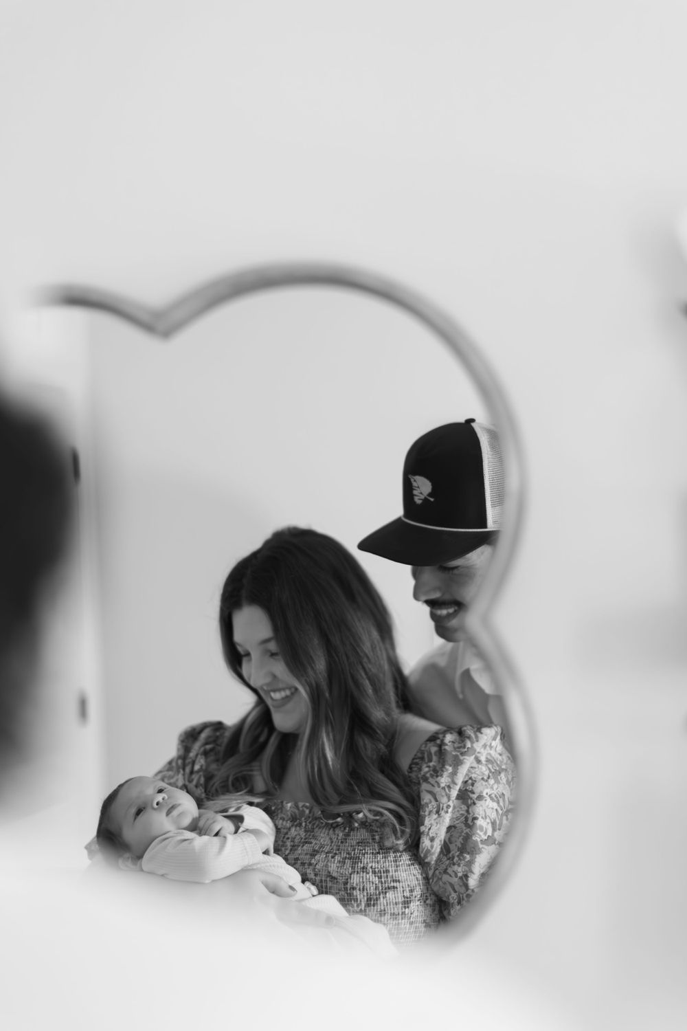 Black and white image viewed through heart-shaped frame showing tender family moment.