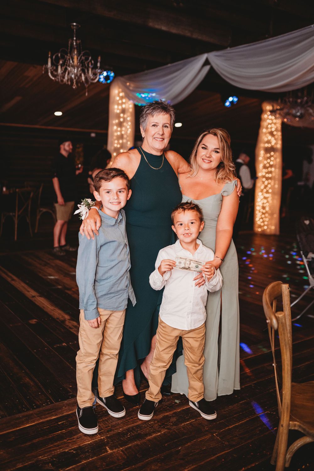 A family group poses together on the wooden dance floor at a wedding reception.