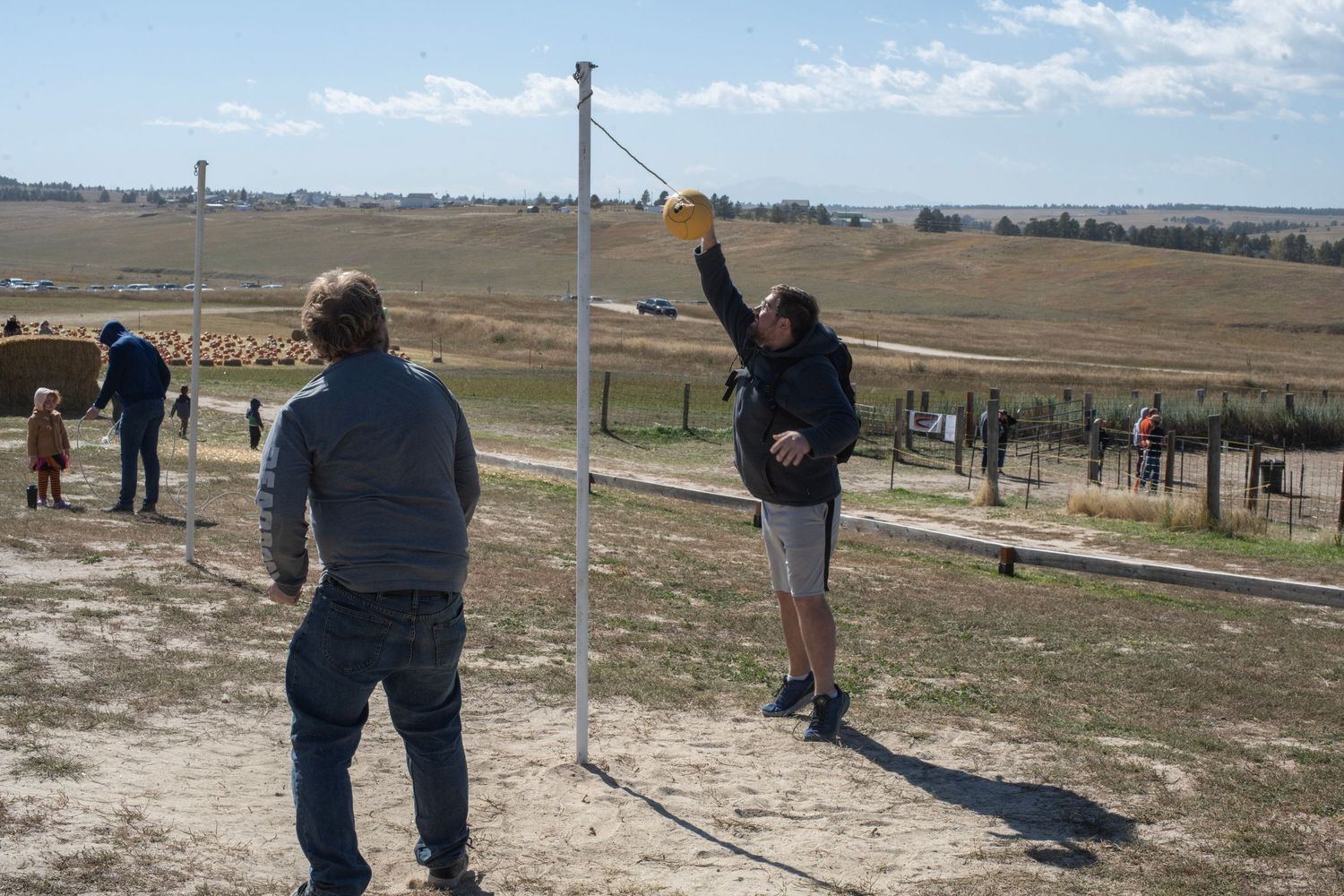 People enjoying clay pigeon shooting at an outdoor range with wide open fields in the background.