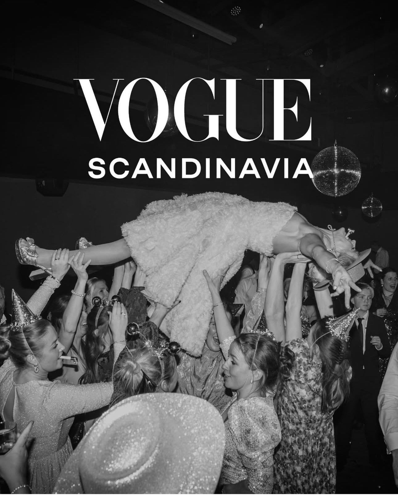 Energetic crowd dancing and celebrating at a nighttime party with Vogue Scandinavia branding visible.