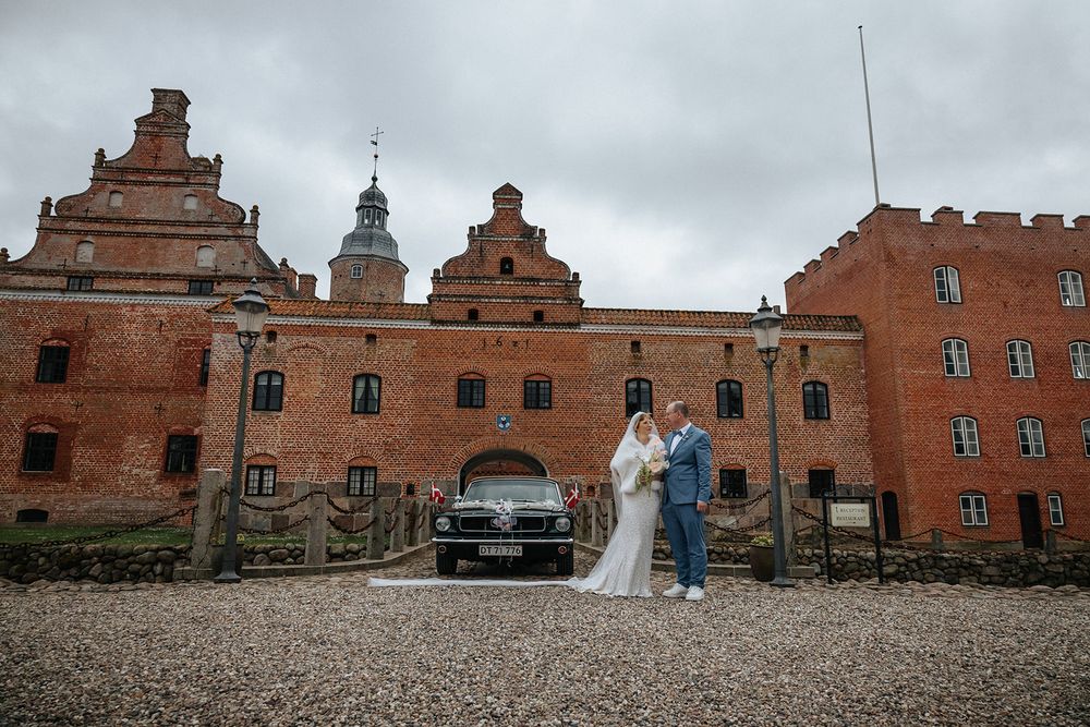 A panoramic view of red brick buildings at Hesselagergaard Manor in Denmark with cloudy skies overhead.