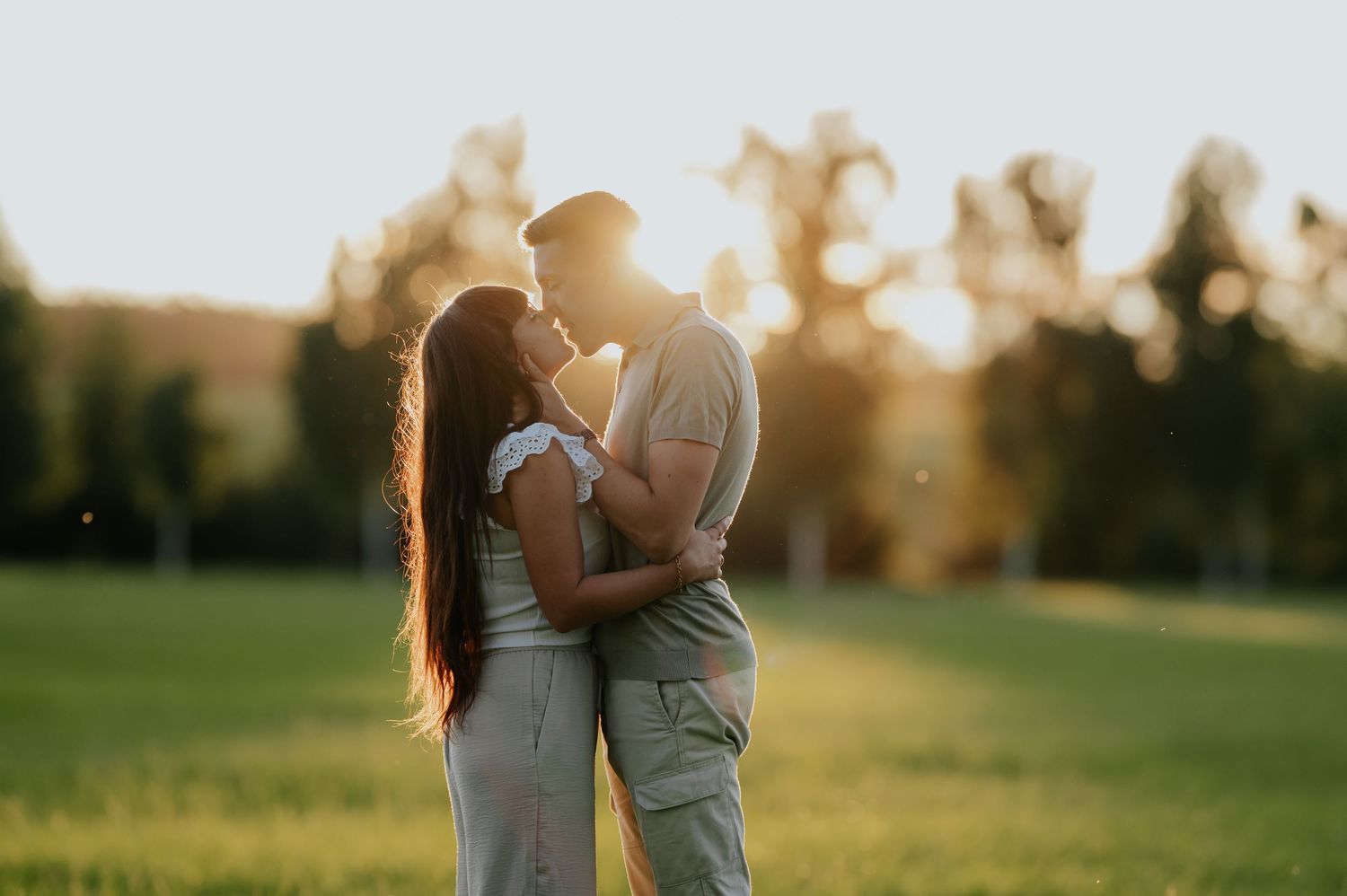 Ein Paar umarmt sich liebevoll in einem sonnenüberfluteten Feld während der goldenen Stunde und bildet eine romantische Silhouette.
