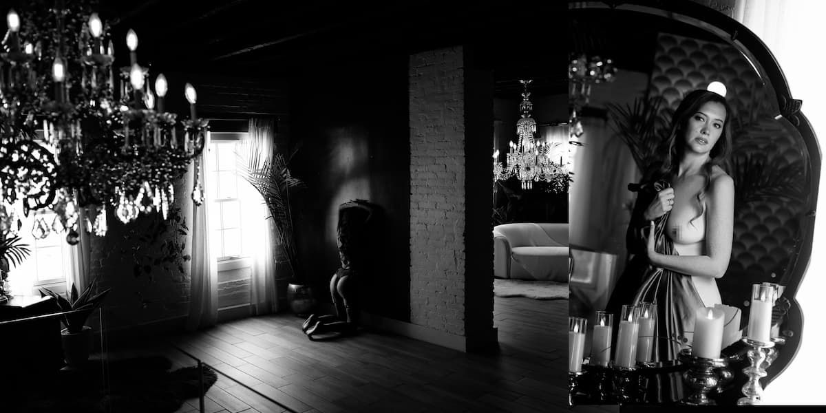 A moody black and white photograph showing multiple silhouettes and light streaming through windows in a dark room.