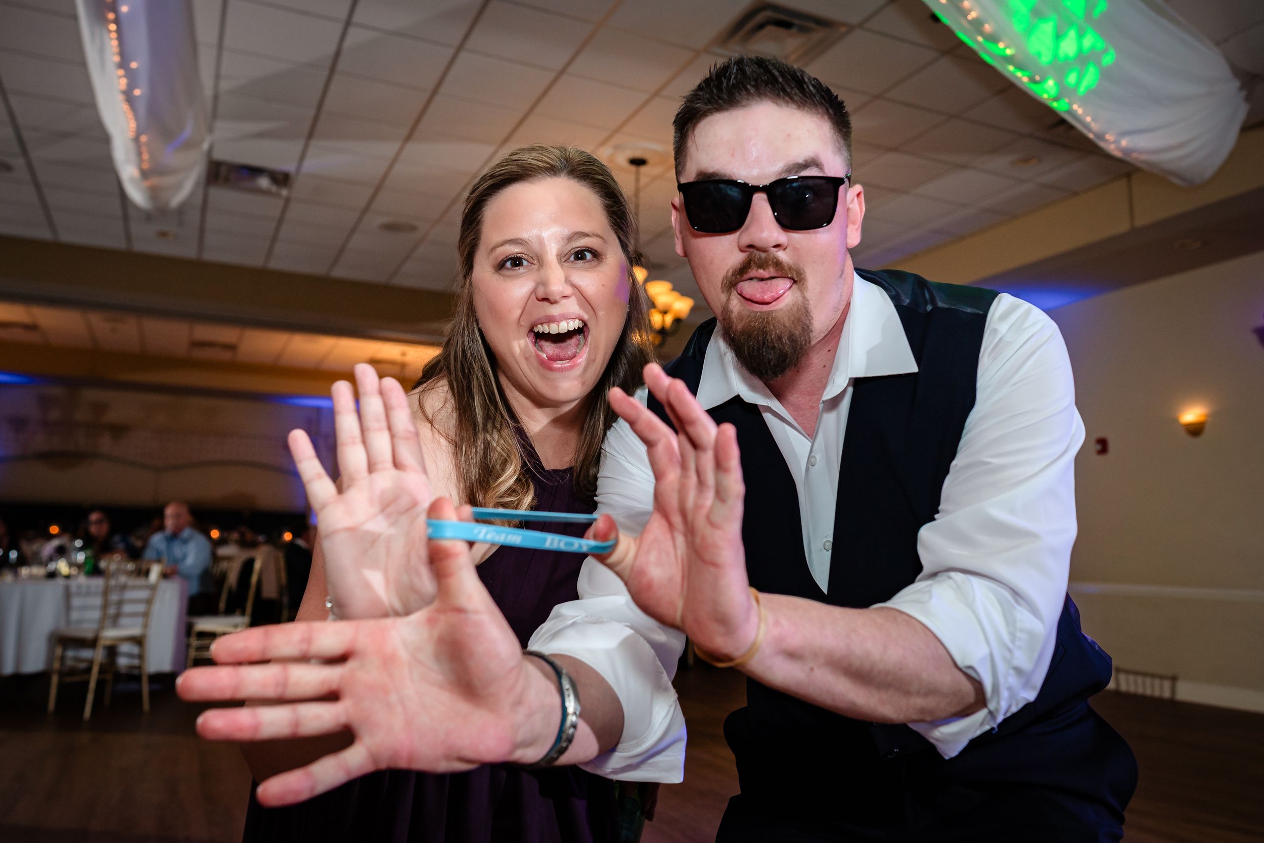 Wedding party members dancing and posing playfully on a dance floor at a reception.