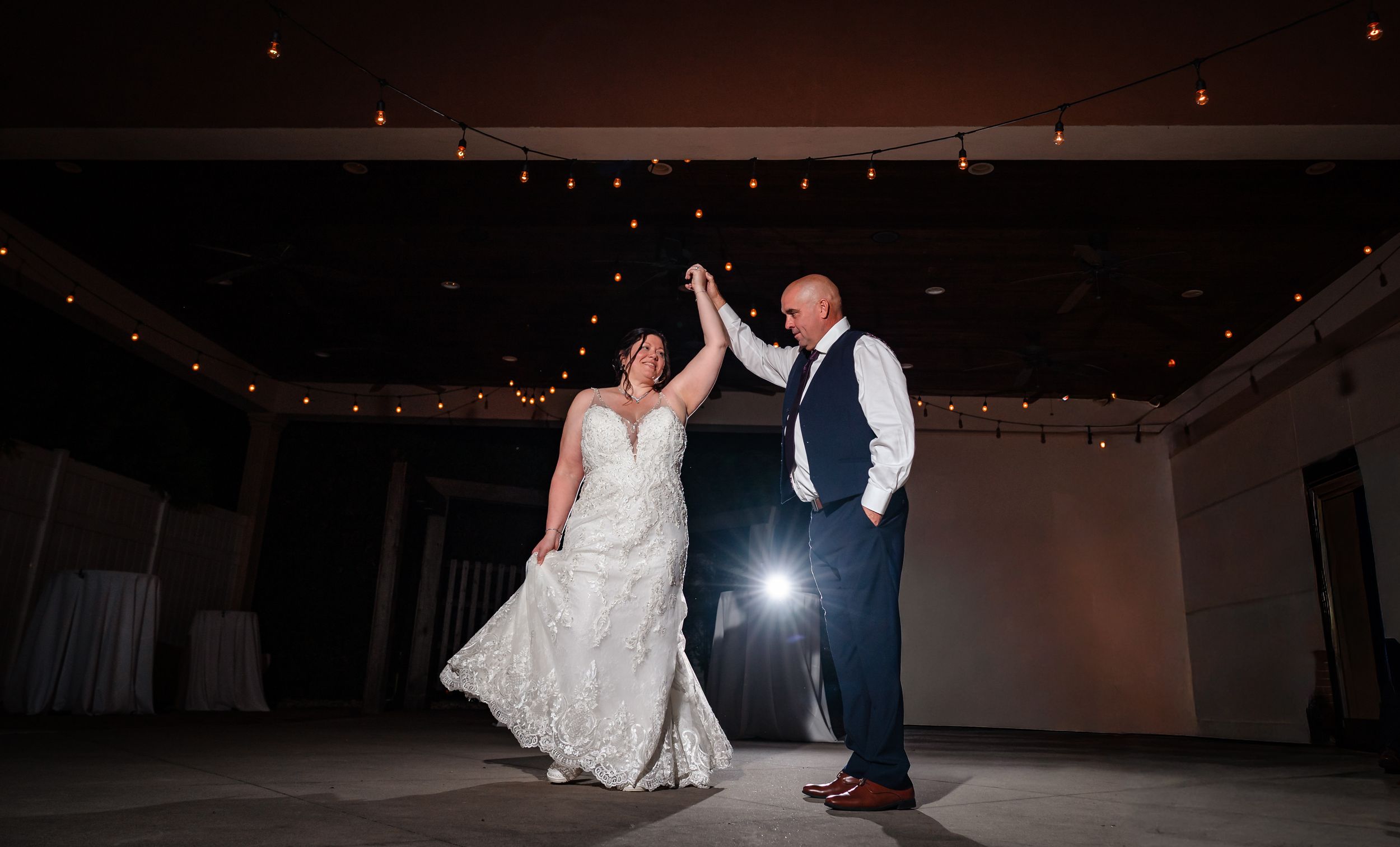Dark dance floor illuminated with string lights during a wedding reception.