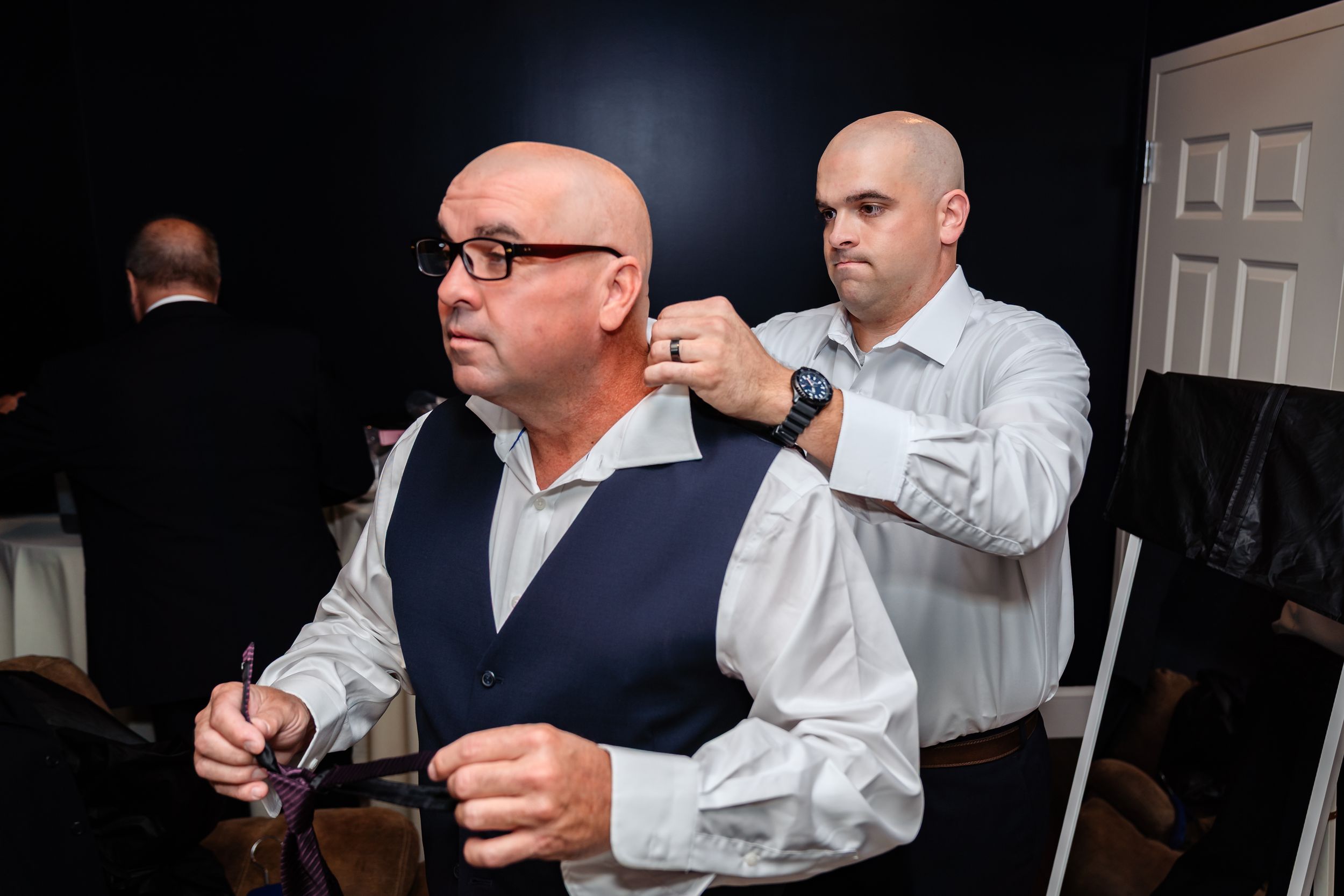 Wedding party members assist with final preparations and adjustments before the ceremony.