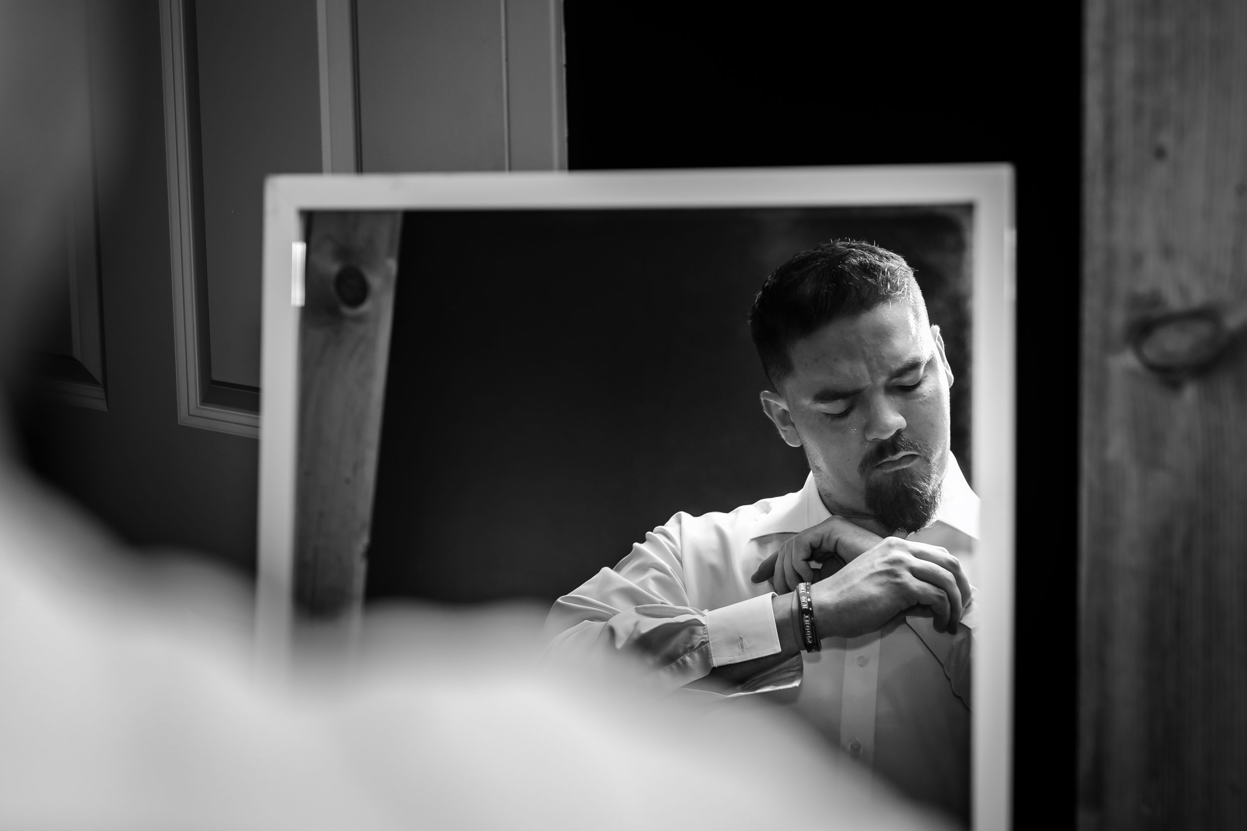 Candid black and white photo of wedding party members helping with pre-ceremony preparations.